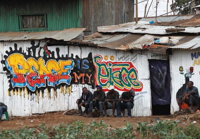 People sit next to a mural advocating for peace after the general election conducted by the Independent Electoral and Boundaries Commission (IEBC) in Kibera slums Nairobi, Kenya