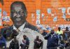 People sit next to a wall mural of Raila Odinga the presidential candidate for Azimio la Umoja and One Kenya Alliance, after the general election conducted by the Independent Electoral and Boundaries Commission (IEBC) in Kibera slums of Nairobi, Kenya